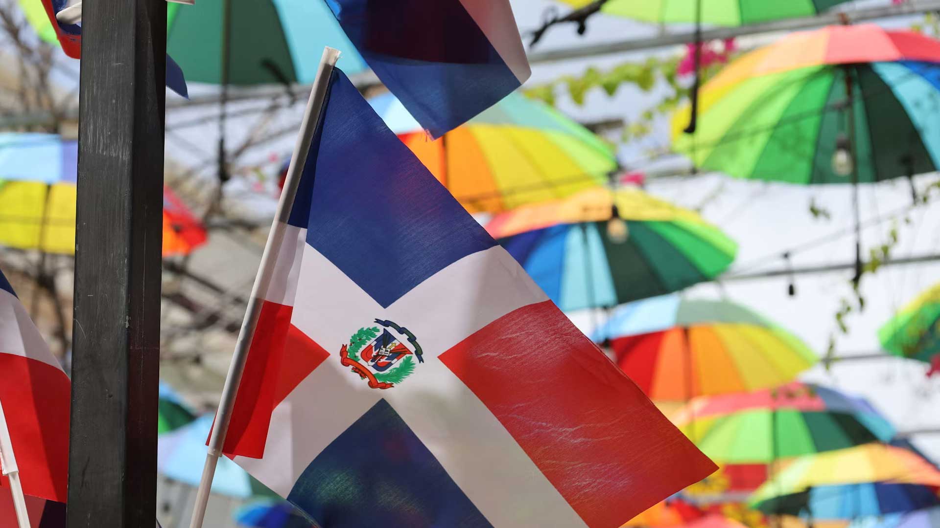 Dominikanische Fahnen vor bunten Schirmen in Puerto Plata