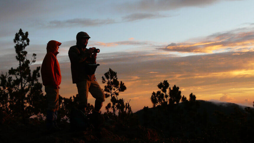 Zwei Reisende fotografieren bei Sonnenaufgang die Berglandschaft am Pico Duarte.