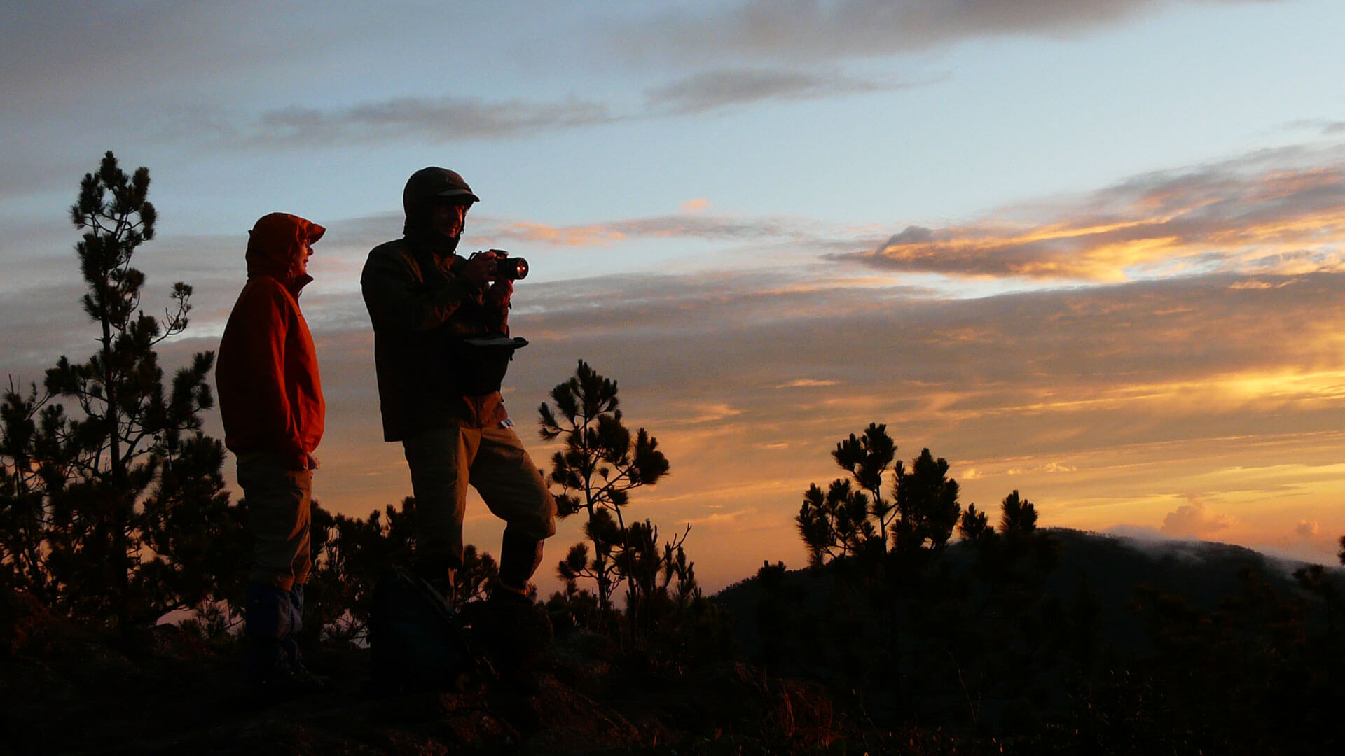 Zwei Reisende fotografieren bei Sonnenaufgang die Berglandschaft am Pico Duarte.